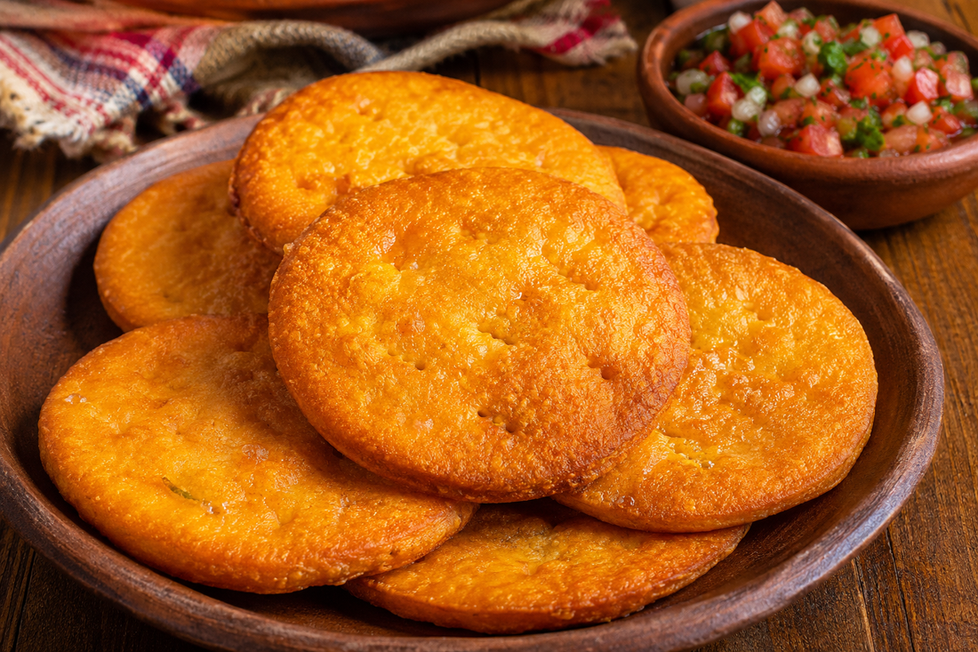 opaipillas chilenas doradas con pebre en pocillo de greda sobre mesa rústica.
